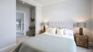 A bedroom with a large bed, two bedside tables, a nightstand, and a door leading to another room. - 311 Superior Maisonette (London)
