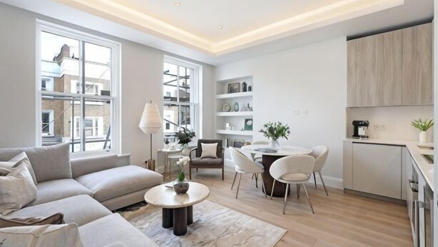 A modern living room with a sofa, coffee table, and dining area. - 311 Superior Maisonette (London)