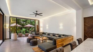 A modern living room with a sectional sofa, a coffee table, and a dining area with a marble table. - Villa Oasis by BaliSuperHost (Bali)