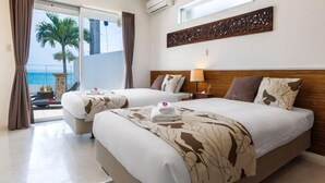 A hotel room with two beds, a large window with a view of palm trees and the sea, and a decorative wall piece above the beds. - Coldio Marina Kin (Kin)