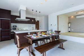 A modern kitchen with a dining area, wooden furniture, and a built-in oven. - Coldio Marina Kin (Kin)