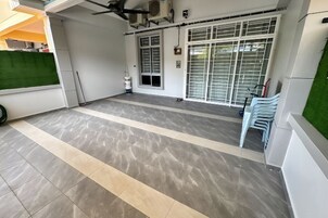 Una habitación amplia con suelo de baldosas, un ventanal con persianas y un ventilador de techo.