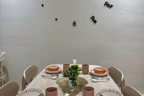 Une table à manger avec des chaises, des assiettes, des tasses et une petite plante.