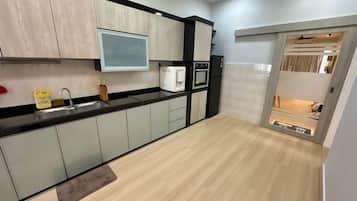 A modern kitchen with a black countertop, stainless steel appliances, and a wooden floor.