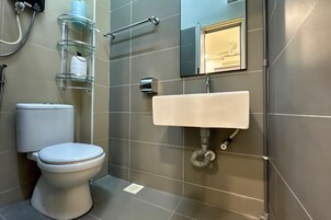 Un baño moderno con inodoro, repisas de vidrio, lavamanos y espejo.