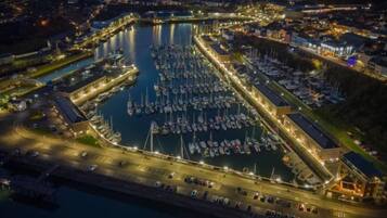 A marina with numerous boats docked, connected piers, and a well-lit waterfront area.