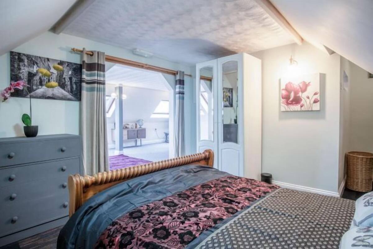 Quarto com cama, penteadeira, espelho e porta que dá para uma varanda.