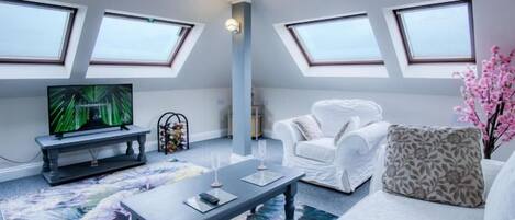 Ein modernes Wohnzimmer mit Flachbildfernseher, einem weißen Sofa, einem Couchtisch und einem großen Fenster.
