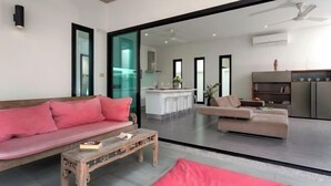 Un salon moderne avec un canapé, une table basse et un coin repas visible à travers une porte vitrée.
