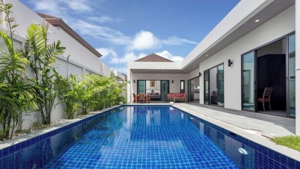 Une maison moderne dotée d’une piscine, d’un coin repas et d’une grande porte-fenêtre coulissante.