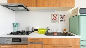 A kitchen with wooden cabinets, a gas stove, a dishwasher, and a sink. - Senju gawaracho 2･3F (Tokyo)
