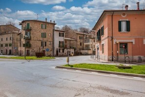 A street view of a town with buildings, a roundabout, and a grassy area. - Smart Room Luxury Rooms with shared kitchen Online check-in (Abbadia San Salvatore)