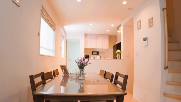 A dining area with a glass-top table, wooden chairs, and a vase with flowers. - Tokyo　Ikebukuro　villa (Tokyo)