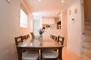 Un comedor con una mesa de vidrio, sillas de madera y un jarrón con flores.