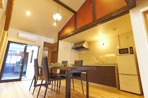 A modern kitchen with a dining area, wooden flooring, and a built-in microwave. - KYOBU Karasuma Gojo (Kyoto)