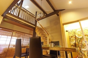 A dining area with a wooden table and chairs, a staircase, and a view of the outside. - KYOBU Karasuma Gojo (Kyoto)