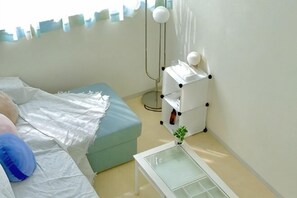 Une chambre à coucher avec un lit, une table de chevet, une lampe et une petite plante.