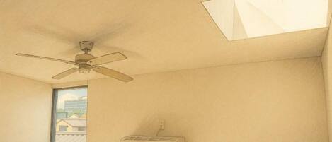 A room with a ceiling fan, a window, and a wall-mounted heater.