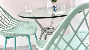 A round glass table with two turquoise chairs, a small potted plant, and a glass on the table. - Only 10 minutes by train to Asakusa & Skytree! (Tokyo)