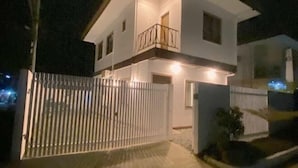 A two-story house with a white exterior, a balcony on the upper floor, and a gated entrance. - Time To Sleep — Casa Ala Una (Butuan)