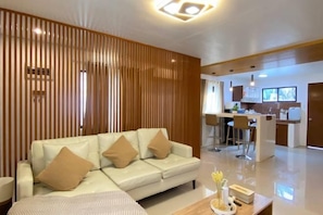 A modern living room with a sofa, a coffee table, and a kitchen in the background. - Time To Sleep — Casa Ala Una (Butuan)