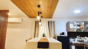 A modern kitchen with a wooden ceiling, a central island with a plant, and a microwave on the counter. - Time To Sleep — Casa Ala Una (Butuan)