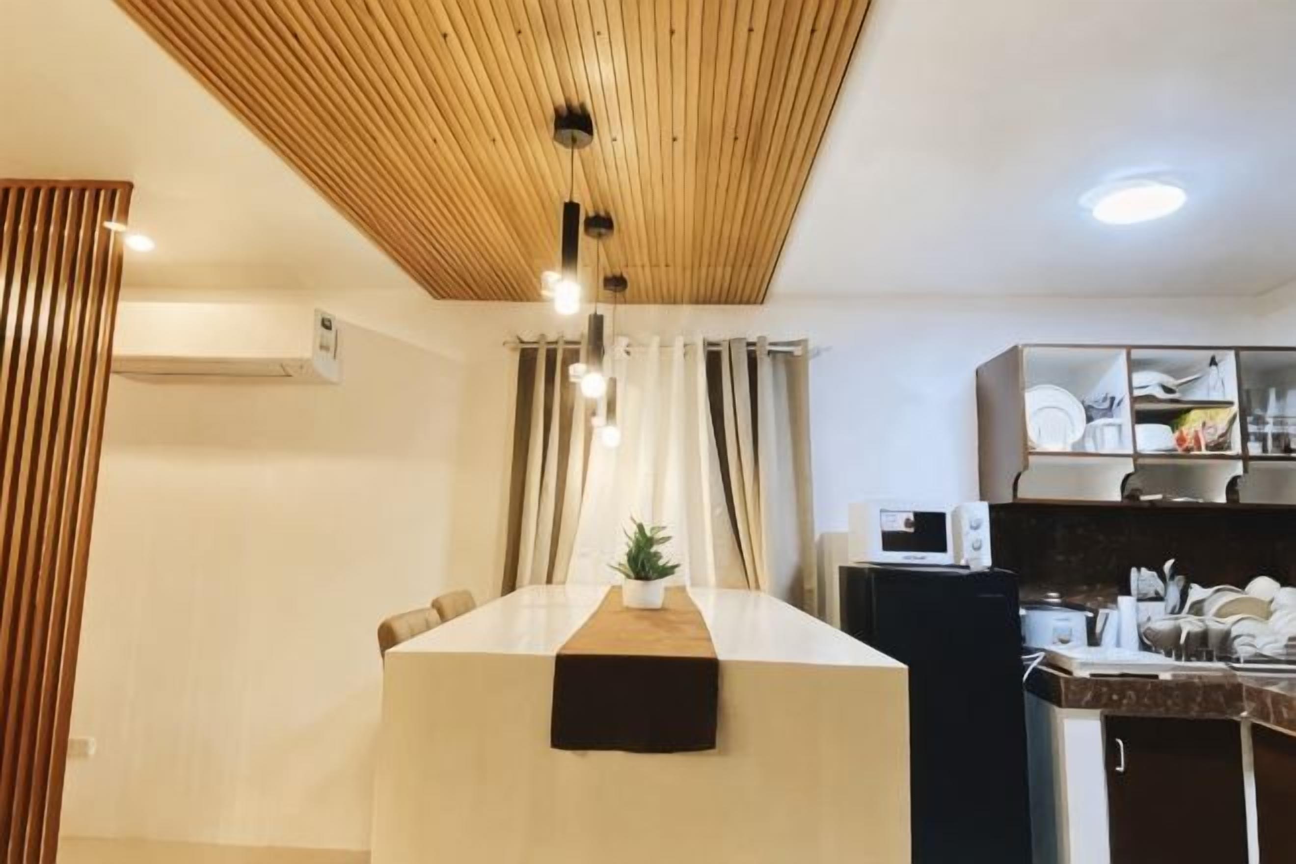 A modern kitchen with a wooden ceiling, a central island, and a dining area.