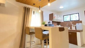 Eine moderne Küche mit Holzbalkendecke, einer Bar mit Hockern und einem Fenster, das für natürliches Licht sorgt.