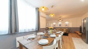 A dining area with a wooden table set for six, white chairs, and pendant lighting. - Spacious 170m² Apartment with AC - Paris Bercy (Paris)