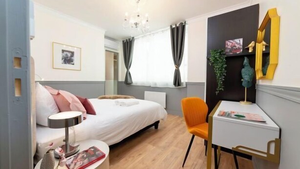 A modern bedroom with a bed, bedside table, chair, desk, and a mirror. - Spacious 170m² Apartment with AC - Paris Bercy (Paris)