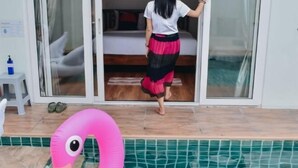 A room with a bed, a sliding door, and a pool area with a pink flamingo float.
