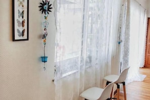 Ein Zimmer mit großem Fenster, Wanddeko und zwei Sesseln.