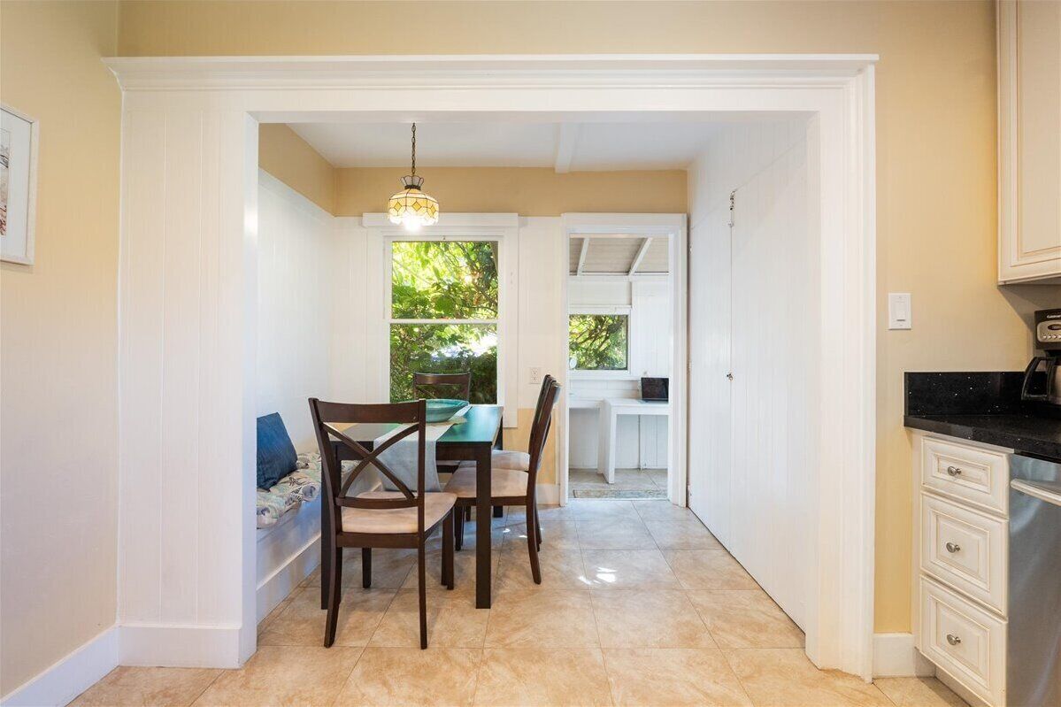 A dining area with a table and chairs, a hanging light fixture, and a view of the outdoors through a window.
