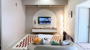 Een moderne woonkamer met een geruit tapijt, een ronde witte tafel en een bank met kussens.