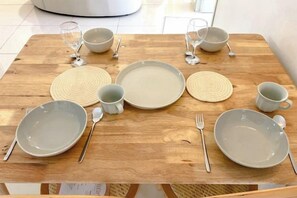 Ein Holztisch gedeckt mit Tellern, Schüsseln, Tassen und Besteck.