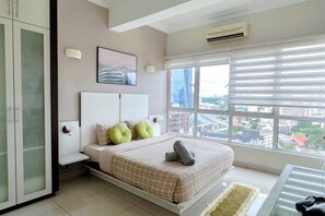 Une chambre à coucher avec un lit, une table de chevet, une fenêtre avec des stores et une vue sur la ville.