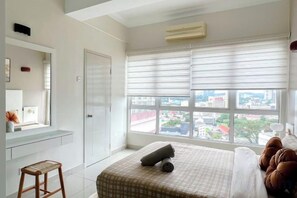 Ein Schlafzimmer mit Bett, Fenster mit Jalousien, Schreibtisch und Stuhl.