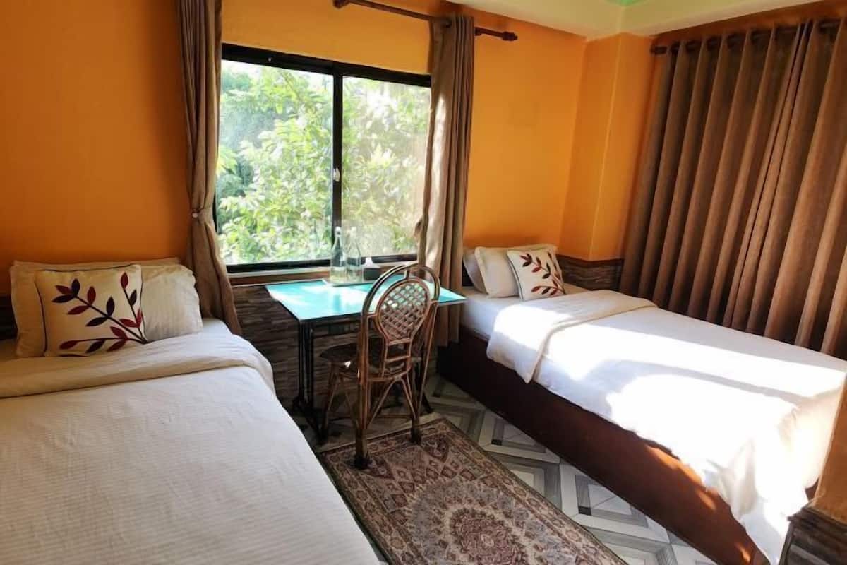 A room with two beds, a table, and a chair.
