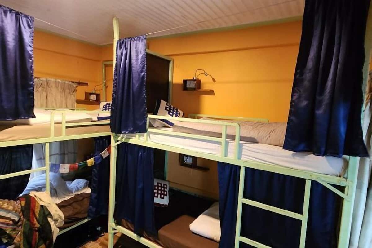 A bunk bed room with curtains, a small shelf with a radio, and a window with curtains.