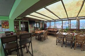 An outdoor dining area with tables and chairs, a brick wall, and a view of the city. - Kiwi Backpackers Hostel Pokhara (Pokhara)