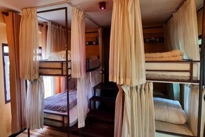 Une chambre avec des lits superposés, des rideaux et une petite table.