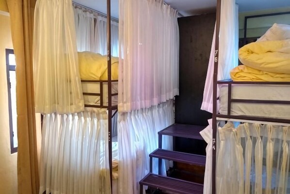 Habitación con literas, ventana, cortinas y una cama con manta amarilla.