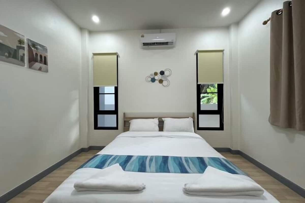 Ein Hotelzimmer mit Bett, Klimaanlage, Jalousien und einem Wanddekor.
