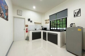Una cocina moderna con una isla central, un refrigerador y una ventana con persianas.
