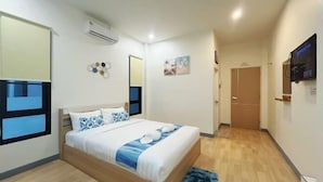 A modern bedroom with a wooden bed, white bedding, a blue accent pillow, a wall-mounted TV, and a small rug. - DelZiaNa Bara Villa Pakbara Satun (La-ngu)