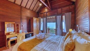 Una habitación de madera con una cama, un escritorio, un espejo y vistas al exterior.