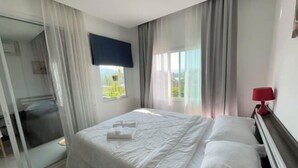 Camera d'albergo con un letto, una lampada rossa e vista sul verde.
