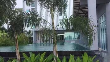 A modern building with a pool, surrounded by greenery.