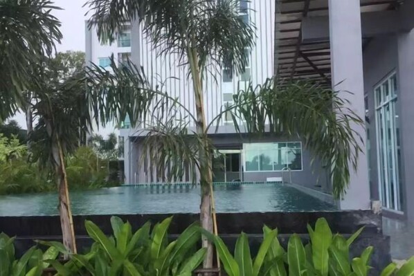 Un edificio moderno con piscina, rodeado de vegetación.
