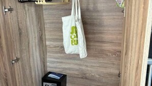Un armadio in legno con una borsa appesa e un oggetto nero sul pavimento.